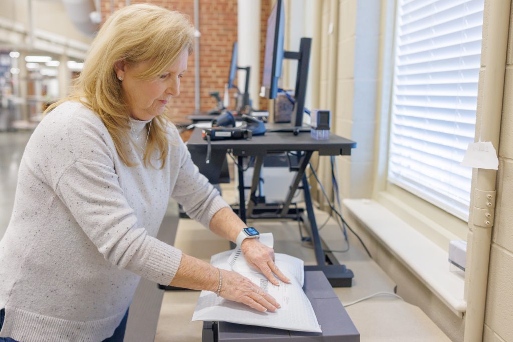 Campus Mail worker putting a shipping label on a package.