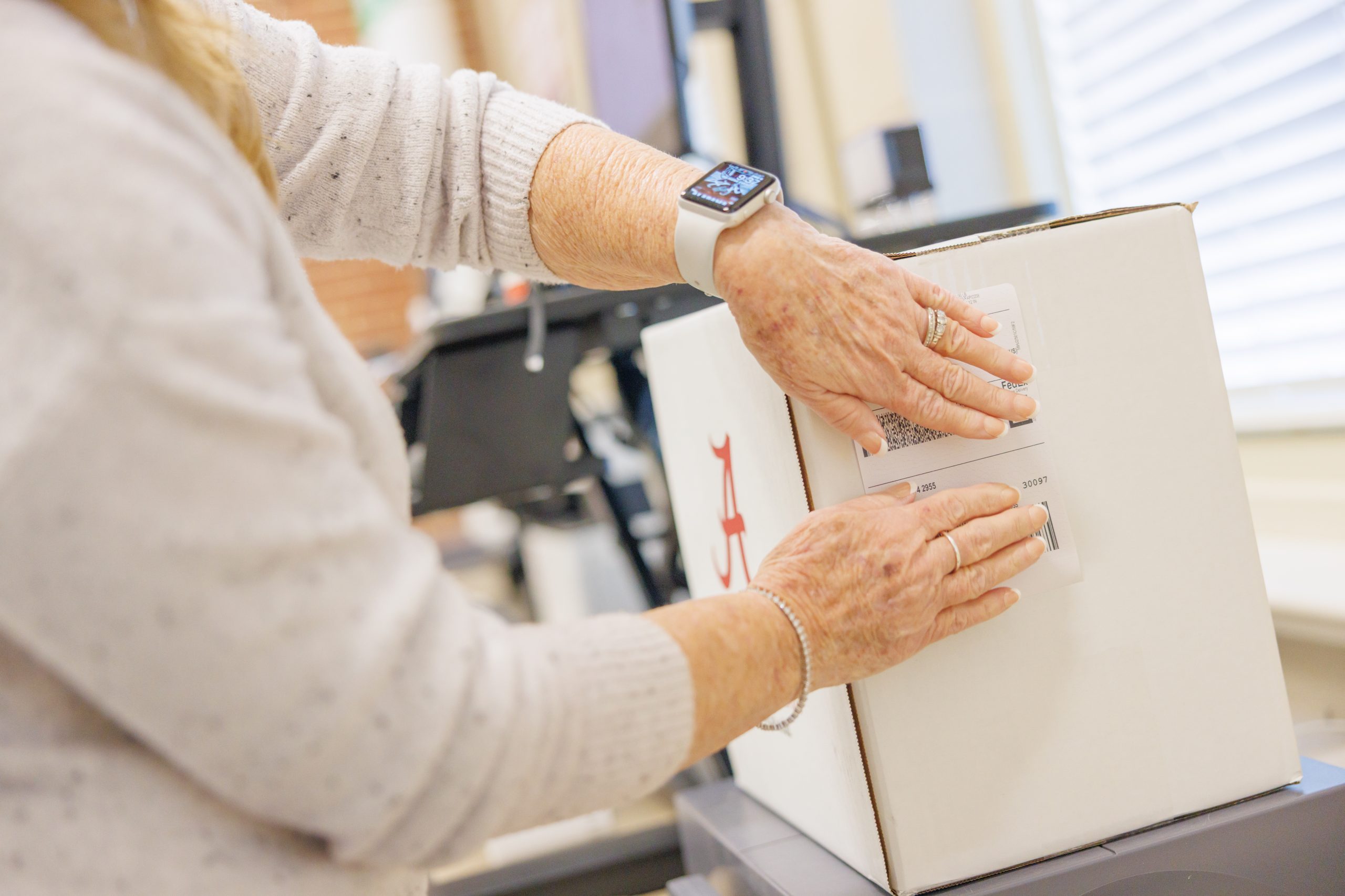 Campus Mail Worker putting a shipping label on a package.